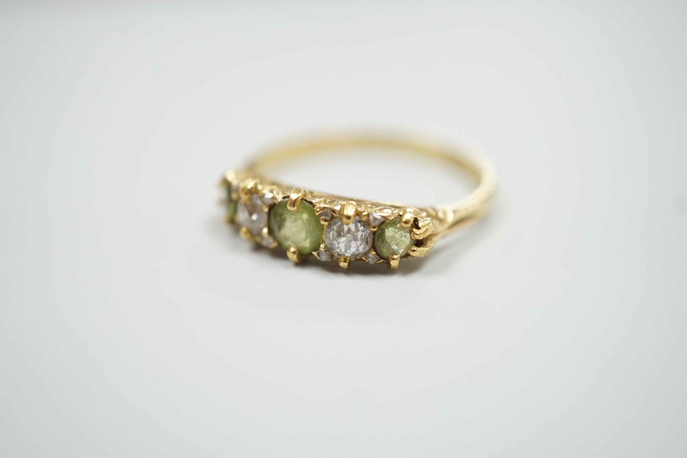 An 18ct, three stone peridot and two stone diamond set half hoop ring. size N, gross weight 2.6 grams.